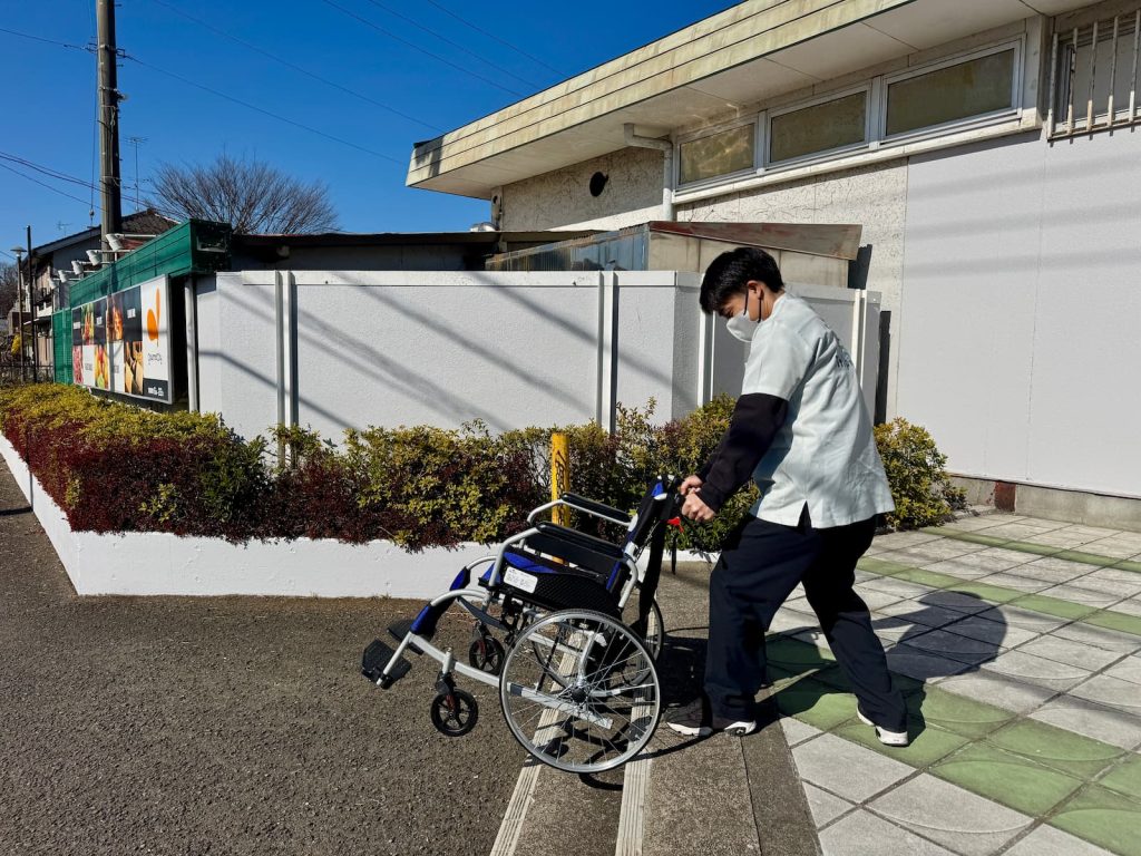 スーパーの階段を活用して、安全確認をしながら車いす階段介助を行う新人スタッフの研修風景