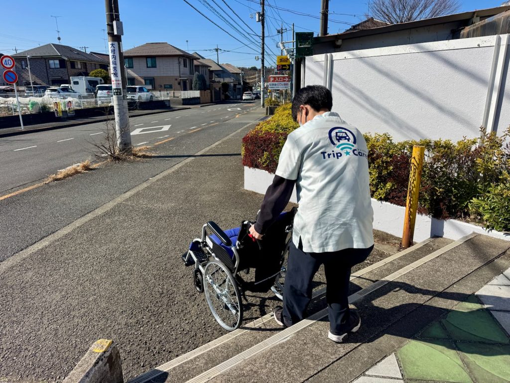 スーバーの段差がある環境を活用して、車いすを使った階段介助を行う福祉介護タクシー Trip☆Care. の新人研修