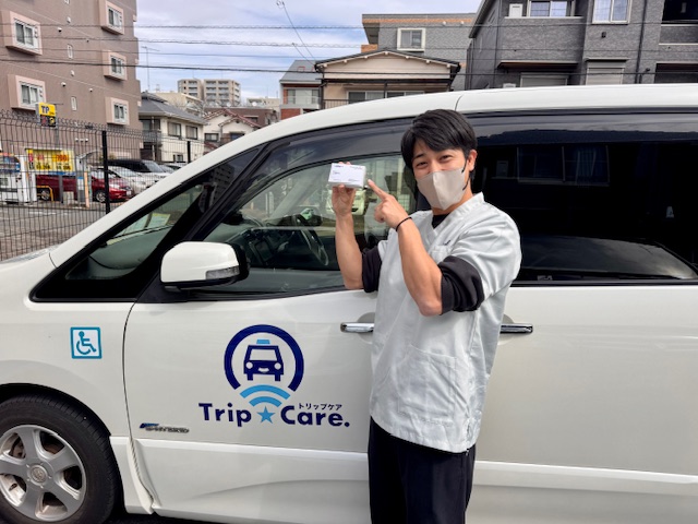 町田店マネージャーの名刺を持つTrip☆Care. スタッフyuyaと福祉介護タクシー車両