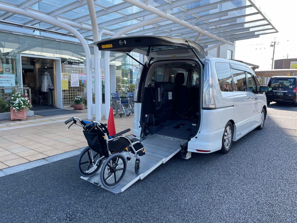 町田市民病院のエントランスにてスロープで車いすを降ろしている福祉介護タクシー車両