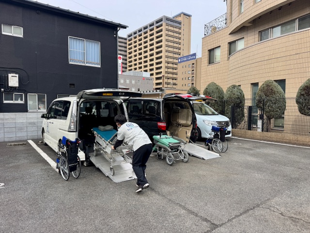 福祉介護タクシー車両にスタッフがストレッチャーとリクライニング車いすを用意する朝の運行前の様子