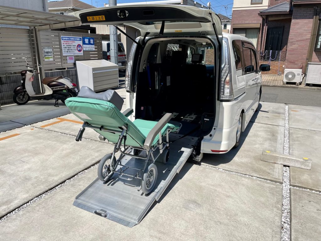 福祉介護タクシー車両（スロープ車両）にリクライニング車いすを乗せる様子