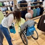 ユニクロで洋服を選ぶ車いすの高齢者と家族