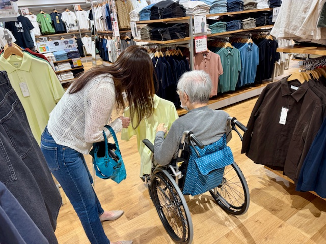 ユニクロで洋服を選ぶ車いすの高齢者と家族