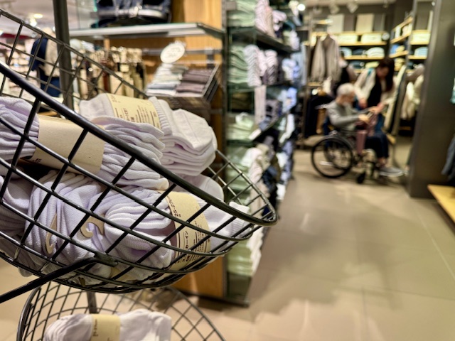 無印良品で買物を楽しむ車いすの高齢者と家族