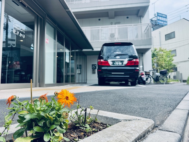足立区にある特養老人ホームはなざかりの花壇にお花と奥に福祉介護タクシー車両