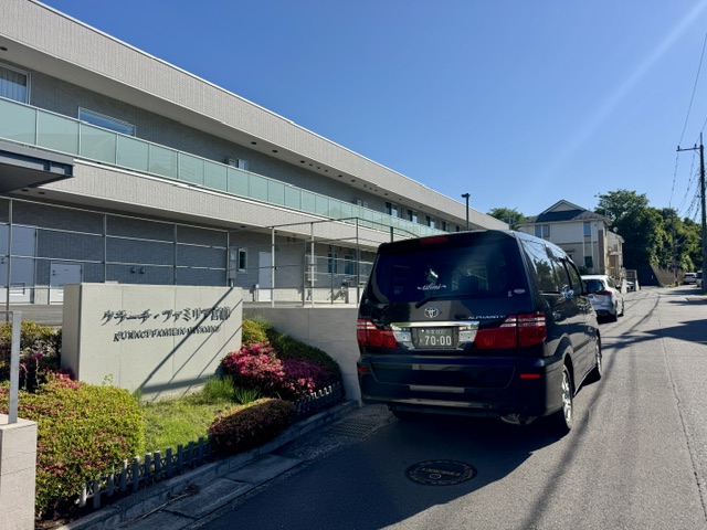 クラーチ・ファミリア外観と看板前に福祉介護タクシー車両